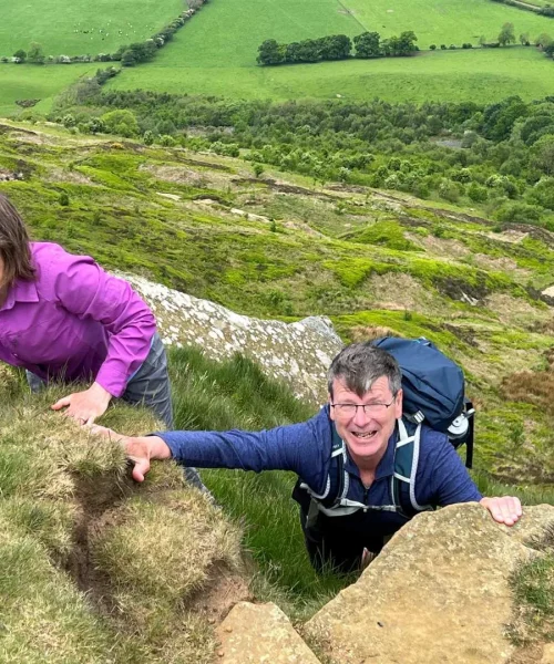 Couple climbing up coast to coast mountainside